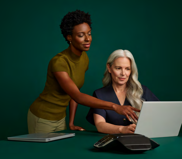 Two women looking at a laptop together. Building trust and confidence in autonomous coding with Solventum | White Paper